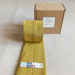 جزییات پشت کراوات لینن یونیسکس به رنگ خردلی (طلایی قدیمی) با تگ برند زی