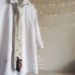جزییات کراوات فانتزی نقاشی شده چهیرو لینن یونیسکس با رنگ سفید و با طرح انیمه شهر اشباح ساخته میازاکی نقاشی شده با دست بسته شده روی پیرهن