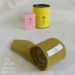 جزییات پشت کراوات لینن یونیسکس به رنگ زرد تیره با تگ برند زی