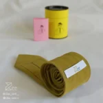 جزییات پشت کراوات لینن یونیسکس به رنگ زرد تیره با تگ برند زی
