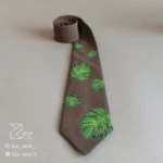 جزییات کراوات خاص هنری و فانتزی لینن یونیسکس به رنگ قهوه‌ای روشن و با طرح برگ انجیری، چاپ شده