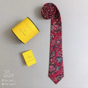کراوات ایرانی بی‌تاب از جنس مخمل با طرح فرش ایرانی با زمینه قرمز لاکی، کراوات مخمل دست‌دوز همراه با جعبه استوانه فلزی نگهدارنده کراوات و دفترچه راهنمای نگهداری