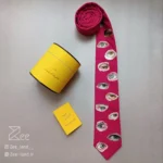 کراوات فانتزی چشم 2 چاپ شده روی لینن سرخابی و با طرح چشم های متفاوت، دست‌دوز و دست‌ساز همراه جعبه استوانه فلزی برای نگهداری کراوات و دفترچه راهنمای محصول