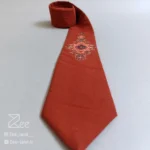 کراوات سنتی قالی ۱ از جنس لینن با طرح الهام‌گرفته از نقوش اصیل فرش ایرانی روی زمینه آجری، چاپ باکیفیت، دوخت کاملاً دست‌دوز از نمای نزدیک