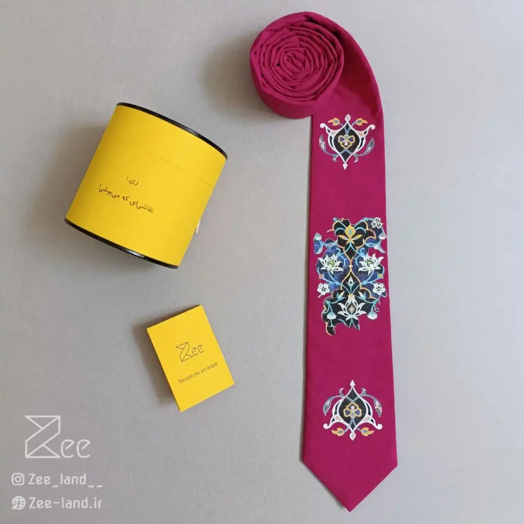 کراوات سنتی کاشی ۱ از جنس لینن با زمینه سرخابی و طرح الهام‌گرفته از کاشی‌کاری ایرانی، چاپ باکیفیت، دوخت دست‌دوز، به‌همراه جعبه فلزی اختصاصی و دفترچه راهنما.