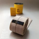 کراوات ایرانی گلیم 1 از نمای پشت، لینن کرم با طرح زرشکی و قهوه‌ای گلیم فرش ایرانی، دست‌دوز و دست‌ساز همراه جعبه استوانه فلزی برای نگهداری کراوات و دفترچه راهنمای محصول